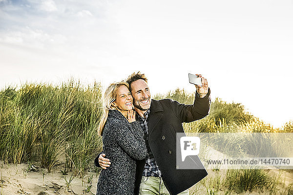 Glückliches Paar in den Dünen beim Selfie
