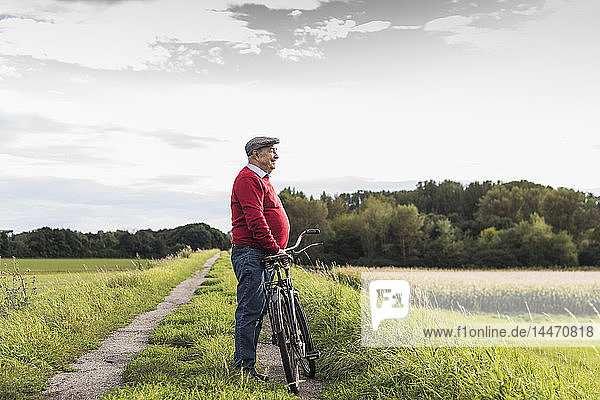 Älterer Mann mit Fahrrad in ländlicher Landschaft
