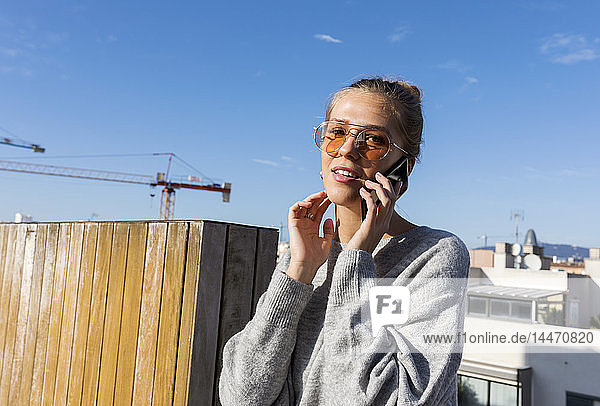 Junge Frau benutzt Smartphone auf einer städtischen Dachterrasse