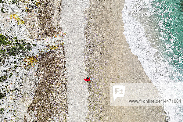 Italy  Elba  woman with red coat walking at beach  aerial view with drone