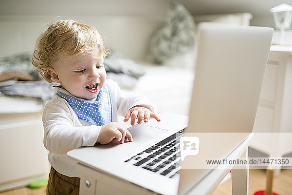Kleiner Junge spielt zu Hause mit Laptop