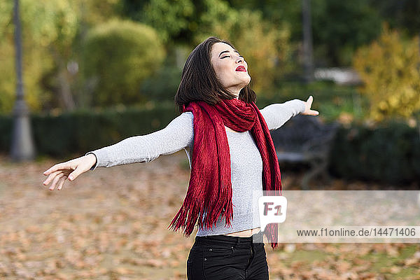 Glückliche junge Frau trägt im Herbst ein rotes Tuch