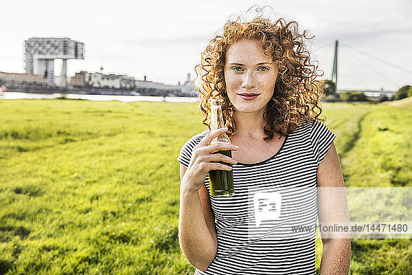Deutschland  Köln  Porträt einer rothaarigen jungen Frau mit Getränk