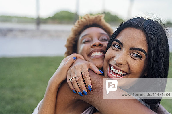 Porträt von zwei glücklichen Freundinnen  die sich in einem Park umarmen