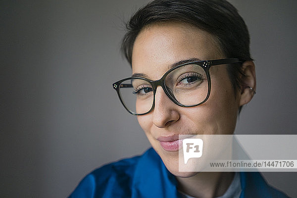 Porträt einer lächelnden jungen Frau mit kurzen Haaren  die eine Brille trägt