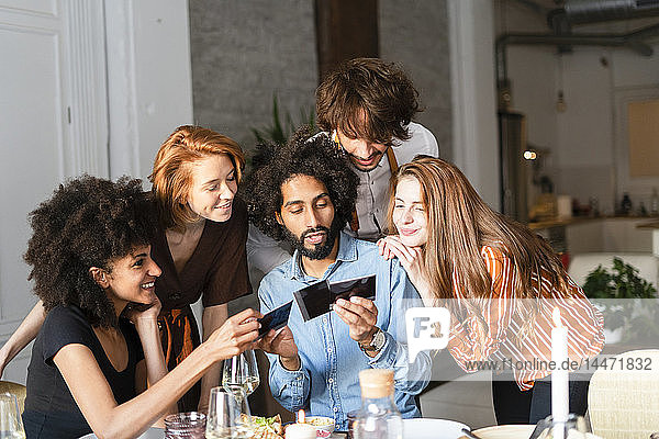 Friends sitting at dining table  looking at photographs