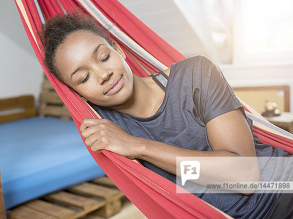 Lächelnde junge Frau schläft in Hängematte