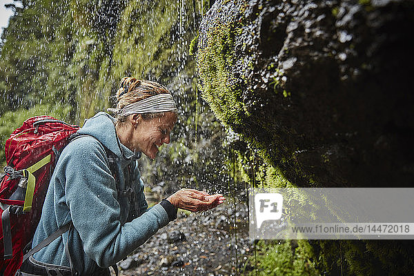 Chile  Patagonien  Vulkan Osorno  Frau erfrischt sich mit Wasser aus dem Wasserfall Las Cascadas