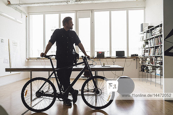 Mann steht mit seinem Fahrrad im Büro