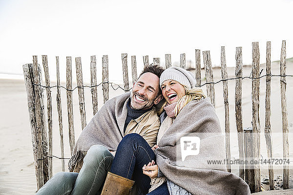 Glückliches Paar in eine Decke gehüllt am Strand