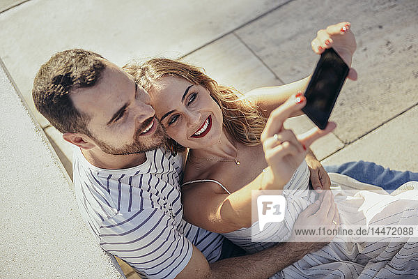 Lächelndes Paar  das sich mit einem Smartphone selbstständig macht