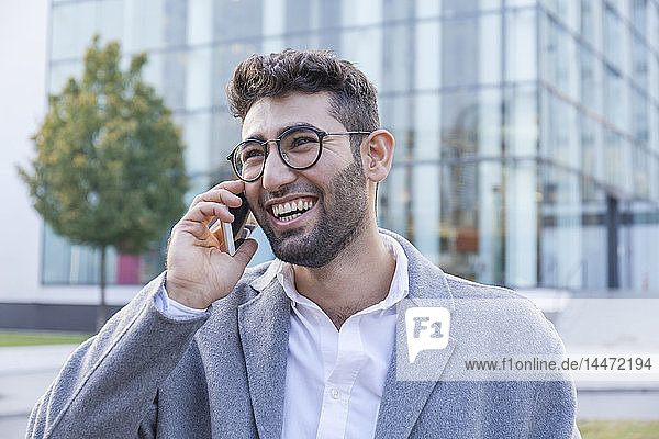 Porträt eines lachenden jungen Geschäftsmannes am Telefon