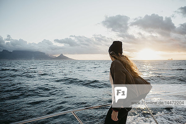 Südafrika  junge Frau mit Wollmütze während einer Bootsfahrt bei Sonnenuntergang