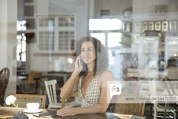 Reife Frau sitzt im Café und telefoniert