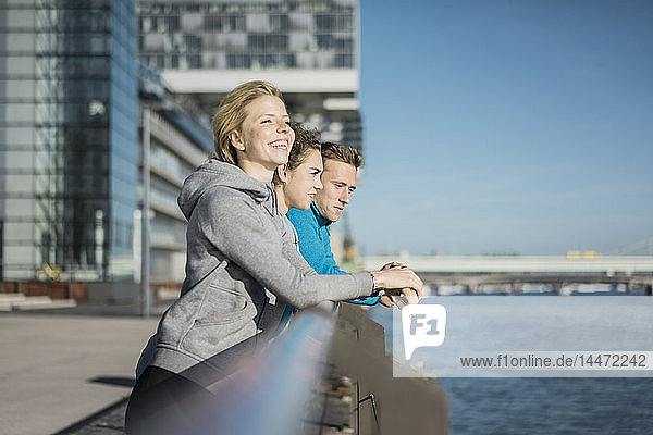 Freunde lehnen sich nach dem Training am Flussufer an ein Geländer