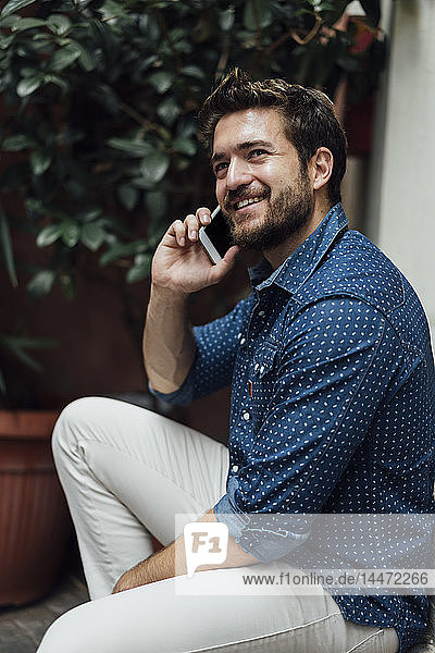 Porträt eines lächelnden Geschäftsmannes am Telefon im Freien