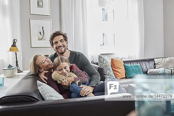 Porträt einer glücklichen Familie  die zu Hause auf der Couch sitzt