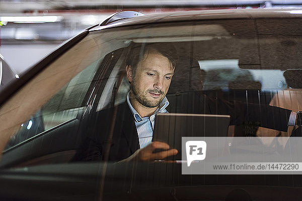 Businessman sitting in car at night  using digital tablet