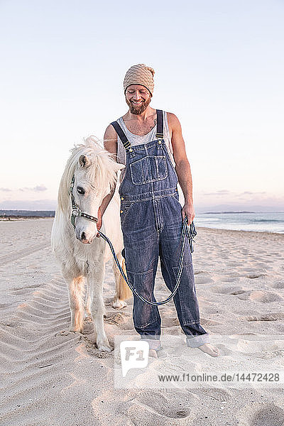 Spanien  Tarifa  lächelnder Mann mit Pony am Strand stehend