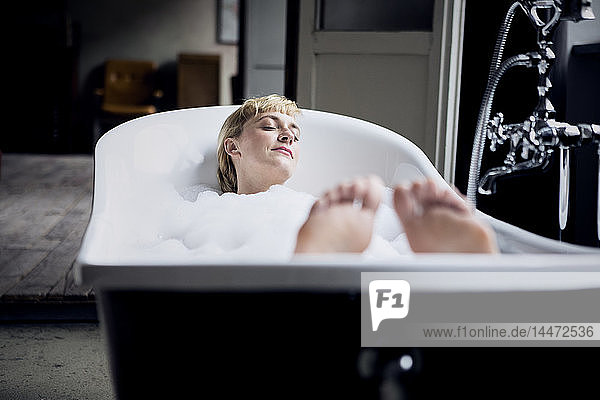 Blond woman taking bubble bath in a loft