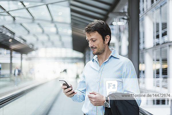 Businessman on a moving walkway  using smartphone