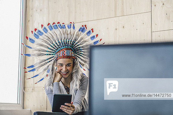Junge Frau trägt indischen Kopfschmuck  steht im Büro und benutzt ein digitales Tablett