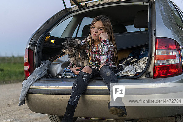 Porträt eines Mädchens im geöffneten Stiefel sitzend mit ihrem Hund  der schmollt