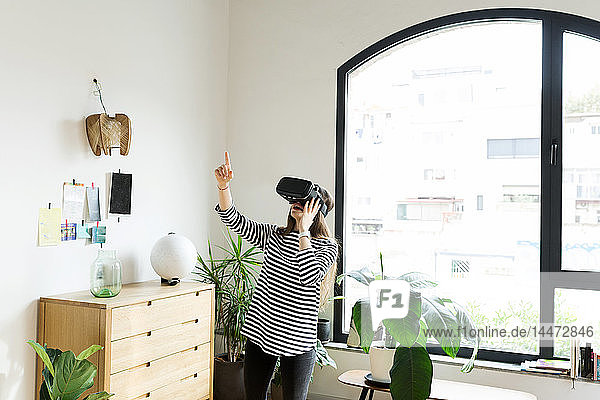 Junge Frau zu Hause mit VR-Brille