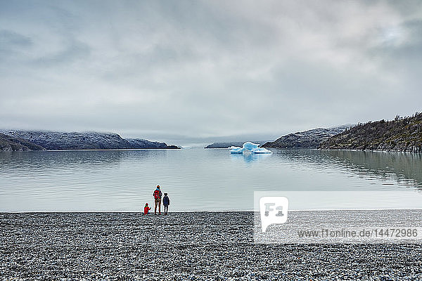 Chile  Torres del Paine Nationalpark  Lago Grey  Frau mit zwei Söhnen steht am Ufer und schaut auf einen Eisberg