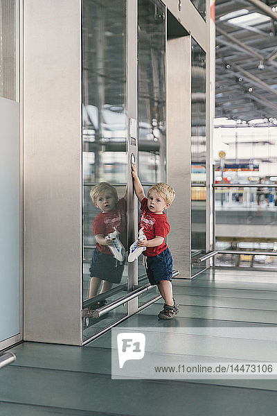 Kleiner Junge drückt Fahrstuhlknopf am Flughafen