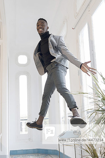 Porträt eines lächelnden jungen Geschäftsmannes  der in seinem Büro in die Luft springt