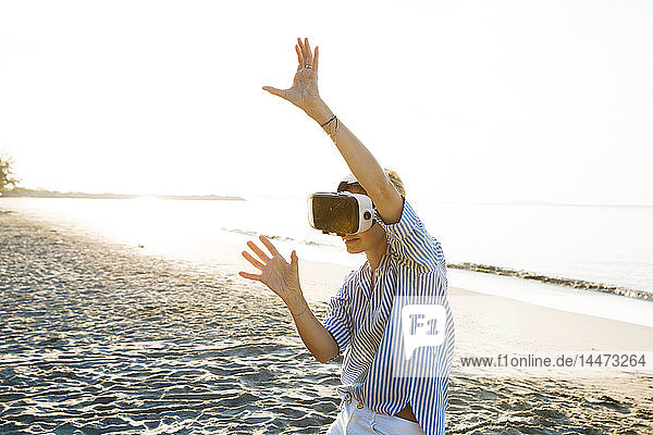 Thailand  woman using virtual reality glasses on the beach in the morning light