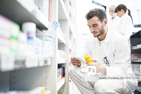 Pharmacist with pill box and prescription in pharmacy