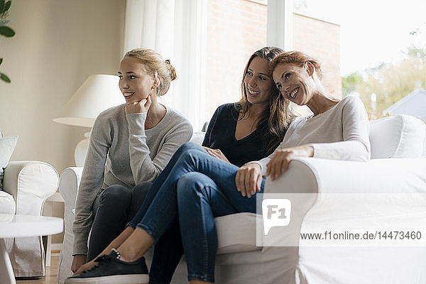 Glückliche Mutter mit zwei Teenager-Mädchen auf der Couch zu Hause