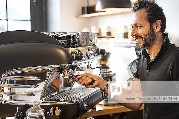 Lächelnder Barista bei der Kaffeezubereitung in einem Café