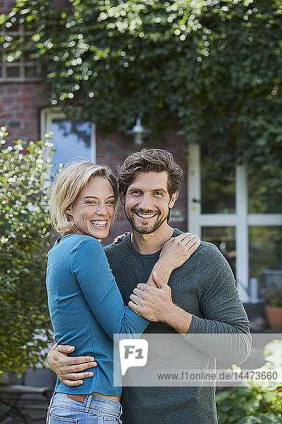 Porträt eines glücklichen Paares im Garten ihres Hauses