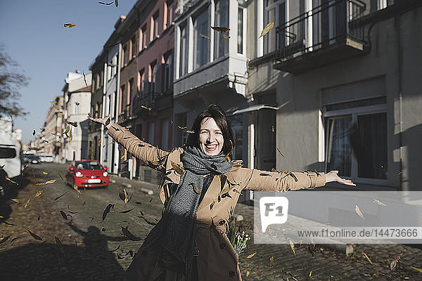 Belgien  Brüssel  Porträt einer glücklichen Frau  die Herbstblätter in die Luft wirft