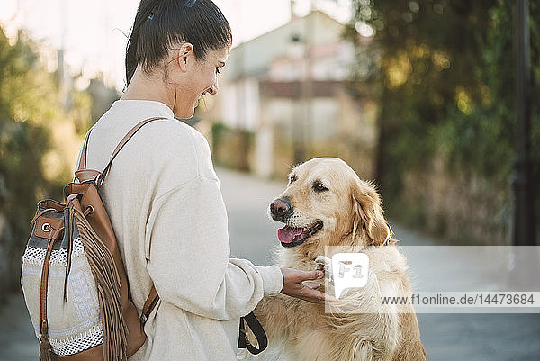 Glückliche junge Frau spielt mit ihrem Golden-Retriever-Hund im Freien