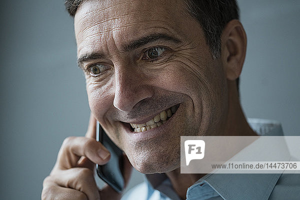 Porträt eines grimassierenden Geschäftsmannes am Handy