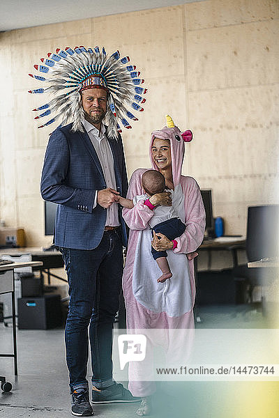 Man and woman  dressed as Indian and unicorn  standing in office  woman holding baby in her arms