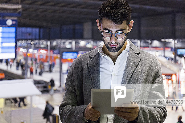 Germany  Munich  young businessman using digital tablet at central station