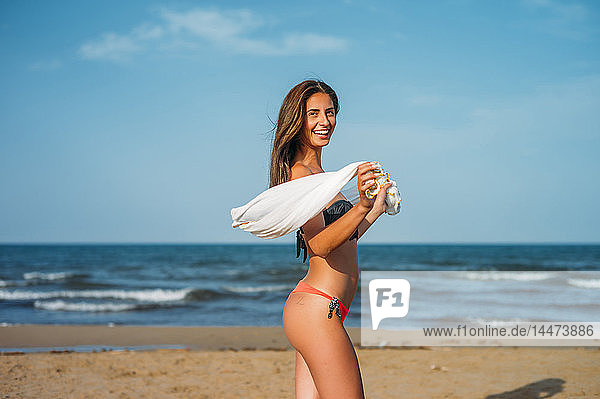 Porträt einer glücklichen jungen Frau im Bikini am Strand