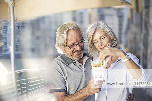 Älteres Ehepaar macht eine Städtereise  isst Pommes Frites