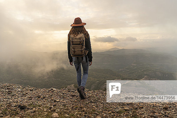 Frau mit Rückenlehne  auf Berg stehend  schaut auf Aussicht