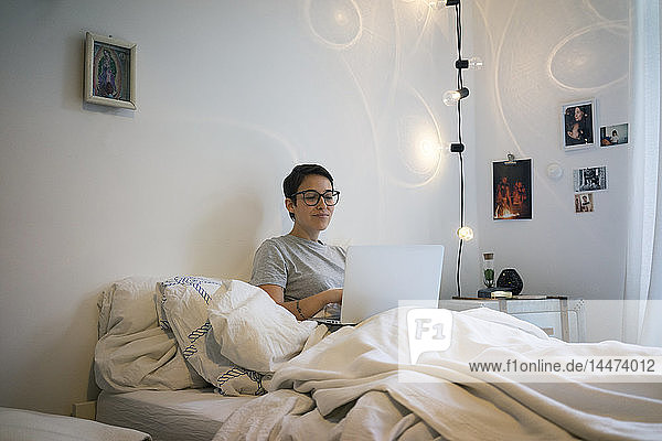 Young woman sitting in bed  using laptop