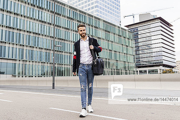 Stylish businessman walking in the city crossing a street