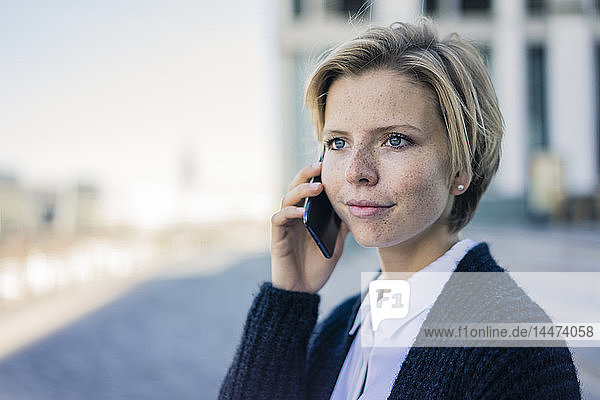 Junge Geschäftsfrau benutzt Mobiltelefon