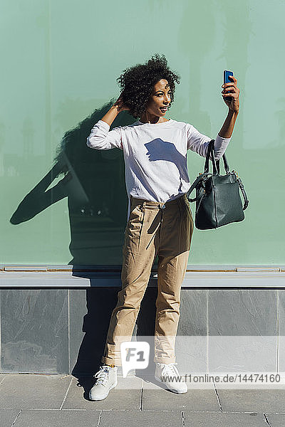 Young casual businesswoman using smartphone in the city  selfie