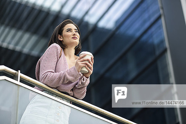 Porträt einer lächelnden jungen Frau mit Kaffee  um auf Distanz zu gehen