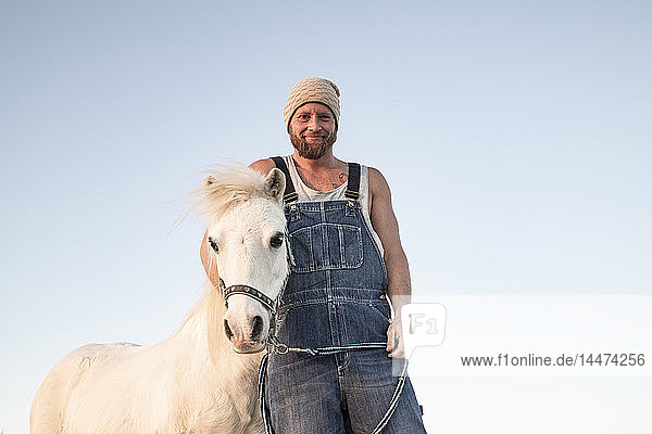 Porträt eines lächelnden Mannes mit Pony unter blauem Himmel